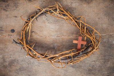 Directly above shot of thorn wreath with cross on wooden table