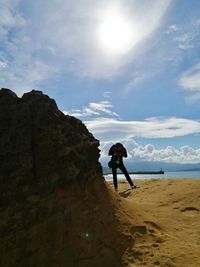 Low angle view of man standing on rock against sky