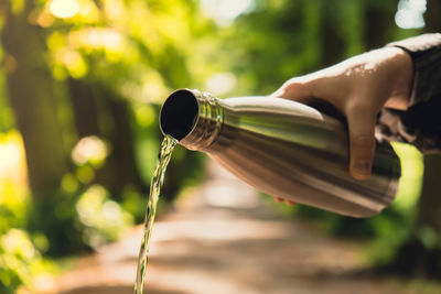 Close-up of unrecognizable female hand holding water bottle. pouring clean water reusable steel