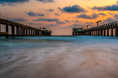 Pier over sea against sky during sunset