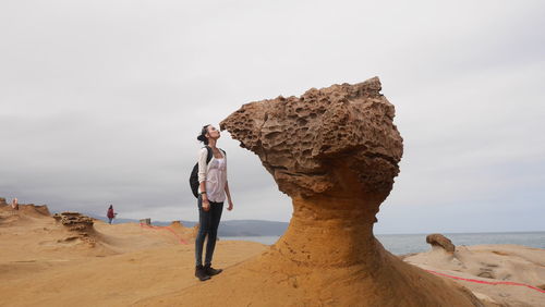 Rear view of man standing at beach against sky