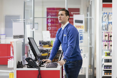 Salesman looking up while standing at counter in store