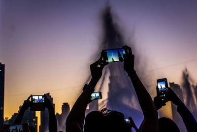 Low angle view of people photographing fountain from mobile phones