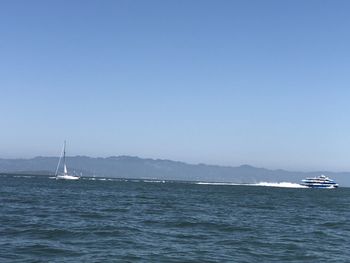 Sailboat sailing in sea against clear sky
