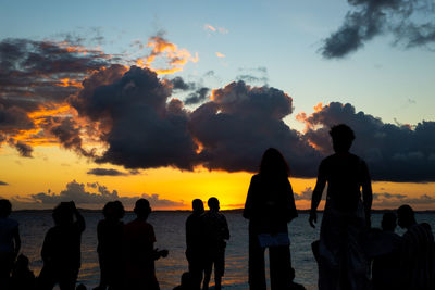 Silhouette people on beach against sky during sunset