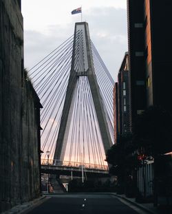 Suspension bridge in city against sky