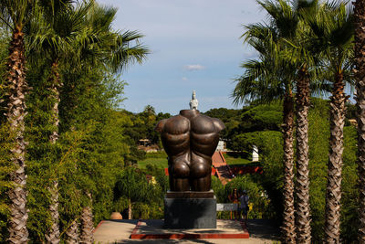 Statue amidst palm trees against sky