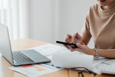 Midsection of woman using laptop on table