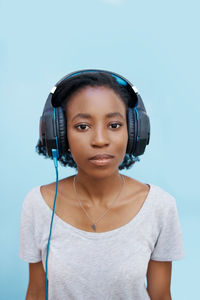 Portrait of woman listening music against wall