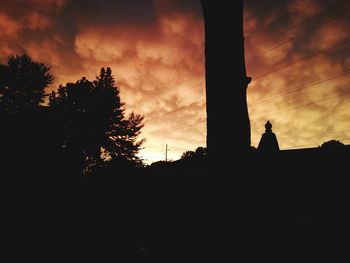 Low angle view of silhouette trees against dramatic sky