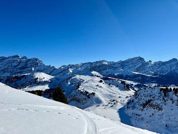 Scenic view of snowcapped mountains against clear blue sky
