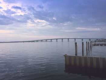 Bridge over bay against cloudy sky during sunset