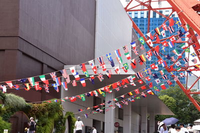 Low angle view of flags hanging amidst buildings in city