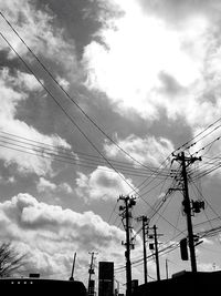 Low angle view of power lines against cloudy sky