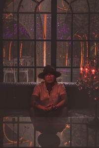 Man wearing hat sitting against window