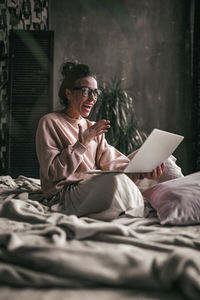 Midsection of woman using mobile phone while sitting on bed