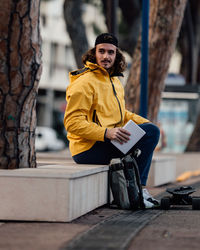 Portrait of man sitting on tree trunk