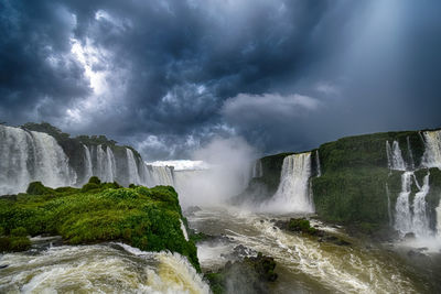 Panoramic view of waterfall against cloudy sky