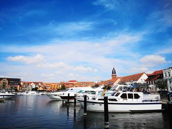 Boats moored at harbor against buildings in city