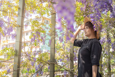 Young woman standing by tree against plants