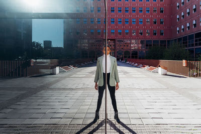 Reflection of young businesswoman on glass wall in financial district