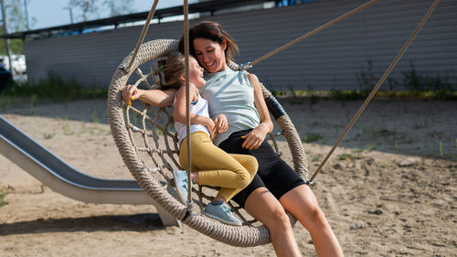 Mother and daughter sitting on swing