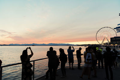 Silhouette people standing at beach during sunset