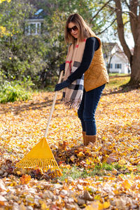 Full length of woman raking at yard