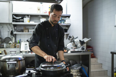 Man working while standing at commercial kitchen