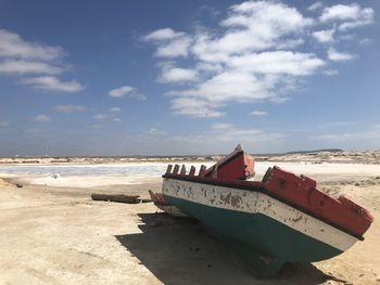 Boat moored on beach against sky