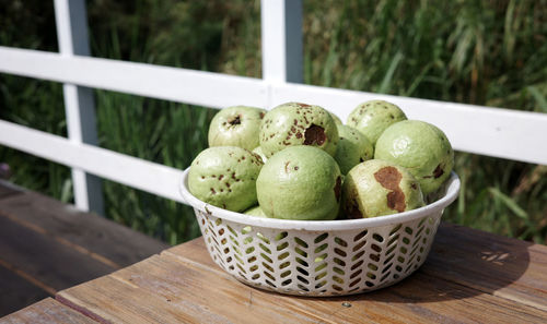 A close-up of a basket of naturally grown guava on a wooden table, harvested in garden