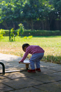 Side view of boy holding umbrella on footpath