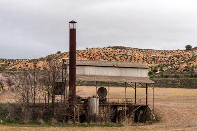 Old abandoned building on field against sky