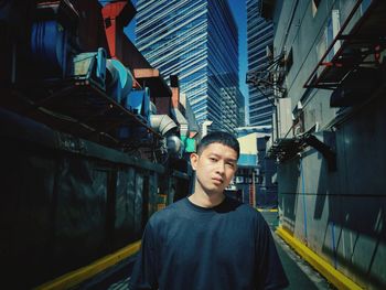 Portrait of young man standing against buildings