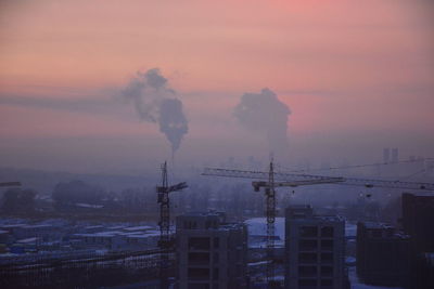 Smoke emitting from factory against sky during sunset