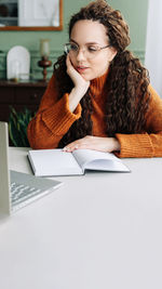 Portrait of smiling young woman using laptop on table