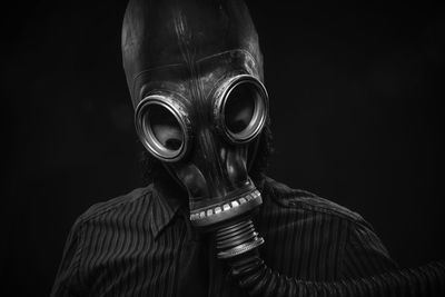 Close-up of man wearing gas mask against black background