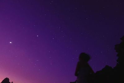 Low angle view of silhouette woman against sky at night