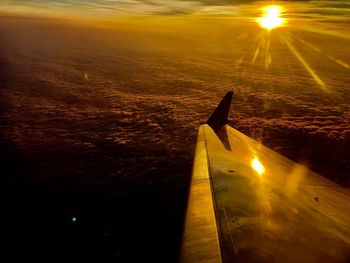 Airplane wing against sky during sunset