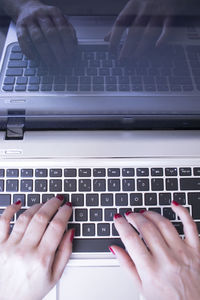 Cropped hands of woman using laptop