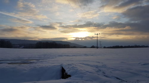 Scenic view of frozen landscape against sky during sunset