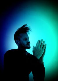 Portrait of young man standing against blue background