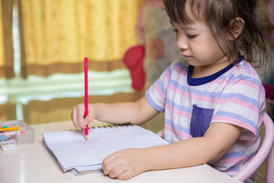 Cute girl holding paper on table