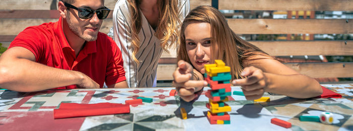 Concentrated woman pushing game piece next to her friends in a rooftop party