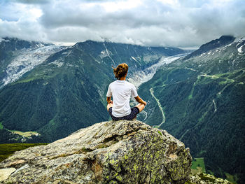 Rear view of man sitting on rock