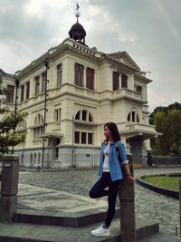 Full length of young woman standing against building