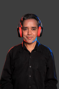 Portrait of smiling man standing against black background