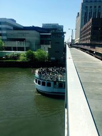 Boats in river by buildings in city against sky