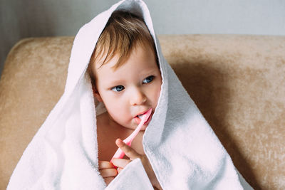 Cute child in big white towel. she brushes his teeth with toothbrush.