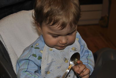 Close-up of cute boy playing with spoon at home